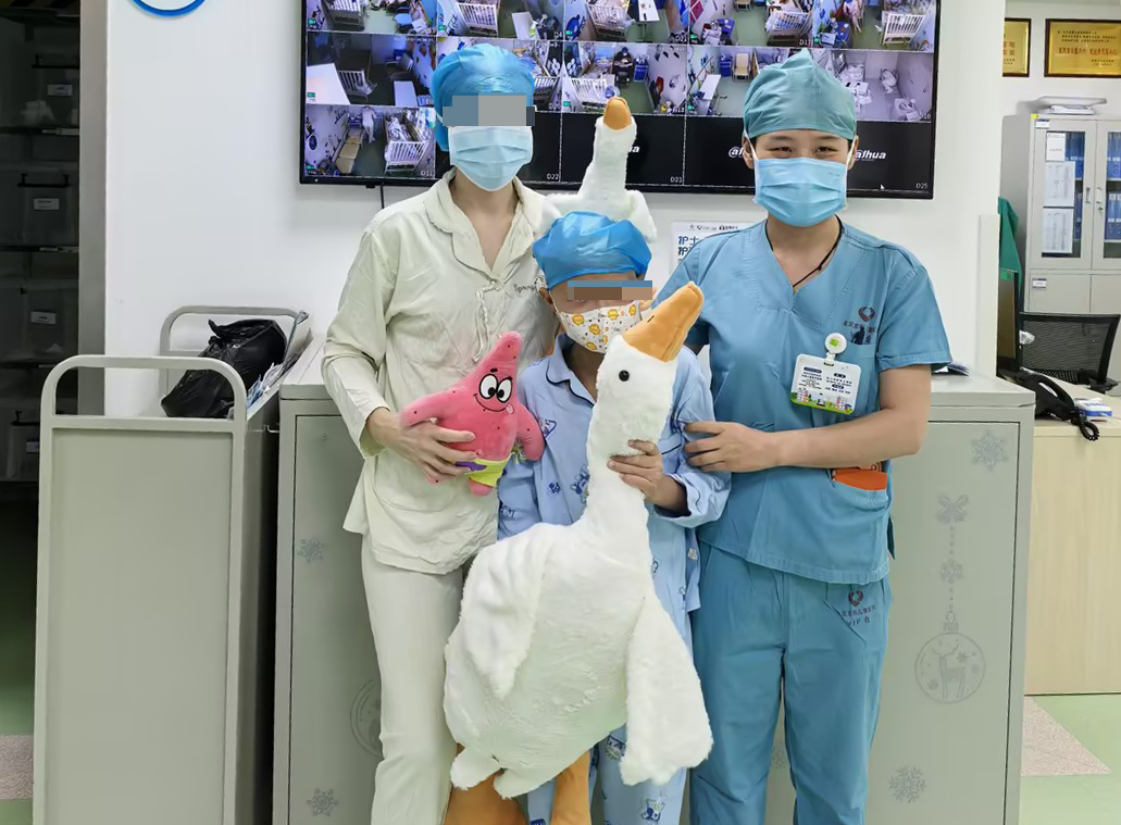 Sasha with his mother and a nurse in the transplant unit, holding comfort toys